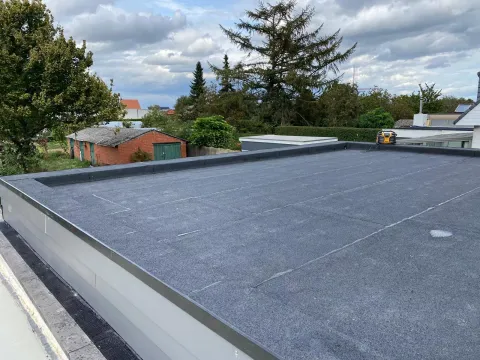 Nieuwe dakrand en goot bij een achterbouw met plat dak